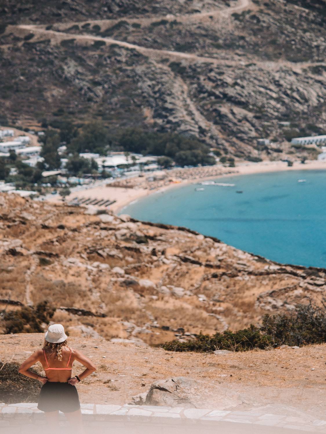 View overlooking MylopotasBeach in Ios, Greece, with turquoise Aegean Sea and rocky Cycladic landscape.